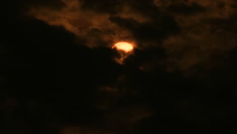 gruesas nubes oscuras se mueven a través de la luna llena naranja a través del cielo nocturno