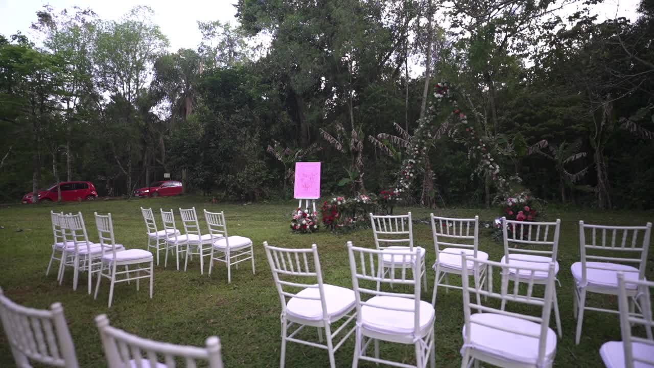 Outdoor wedding ceremony floral arch decoration setup in nature with white chairs