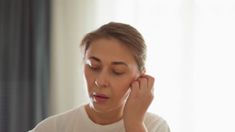 lady dons earbuds jogging at home closeup. sporty woman uses cordless earpieces enjoying music while working out in household gym. fitness life