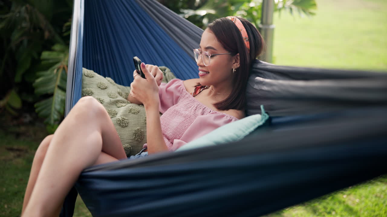 Woman relaxing in hammock with her phone