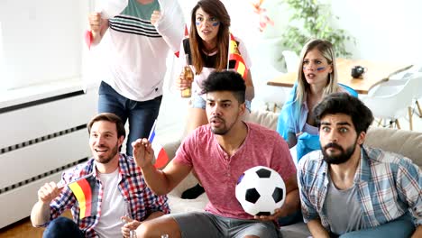 happy friends or football fans watching soccer on tv and celebrating victory at home.