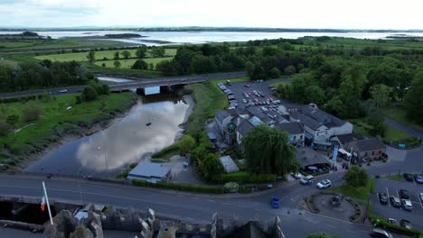 Drone-Hacia-Atrás-Sobre-El-Barrio-Y-El-Castillo-En-El-Exuberante-Pueblo-De-Bunratty-En-Irlanda