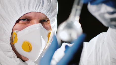 investigador sostiene un frasco de vidrio con reactivos químicos