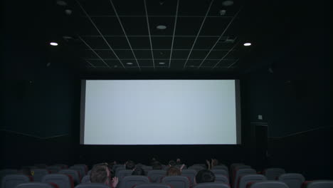 Espectadores-Sentados-Frente-A-Una-Pantalla-Blanca.-Gente-Aplaudiendo-En-El-Cine