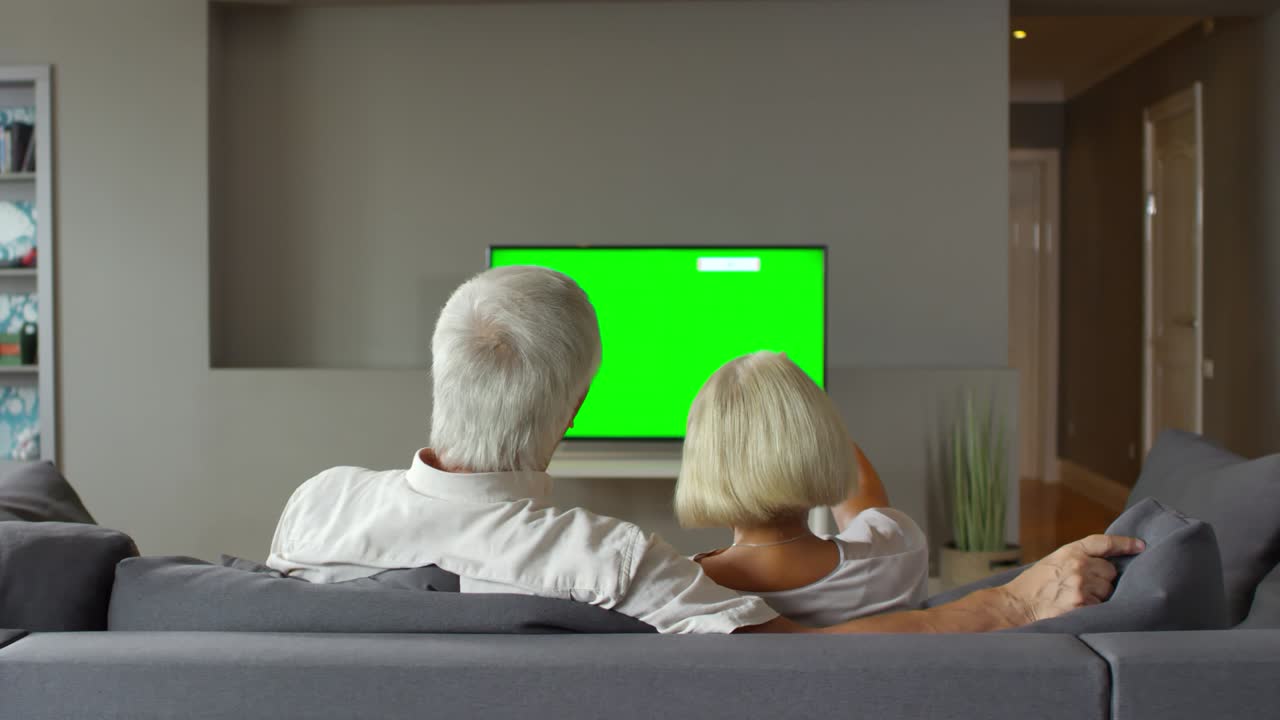 Elderly Couple Watching TV on Sofa at Home
