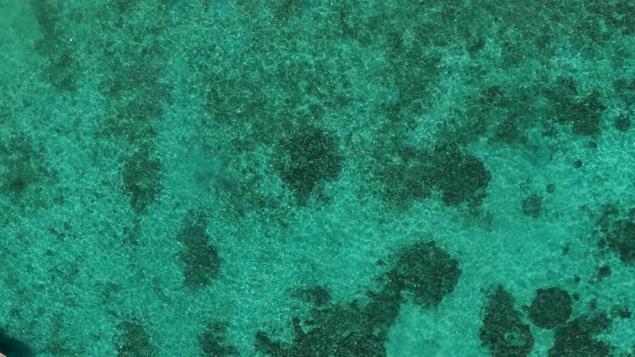 Korkeakulmainen dronekuva näyttää kirkkaan turkoosin veden ja koralliriutat Thaimaassa.
