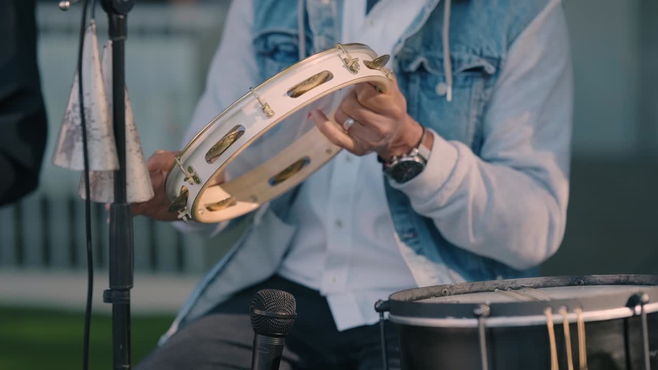 Close up of a musician playing a tambourine during an outdoor live performance