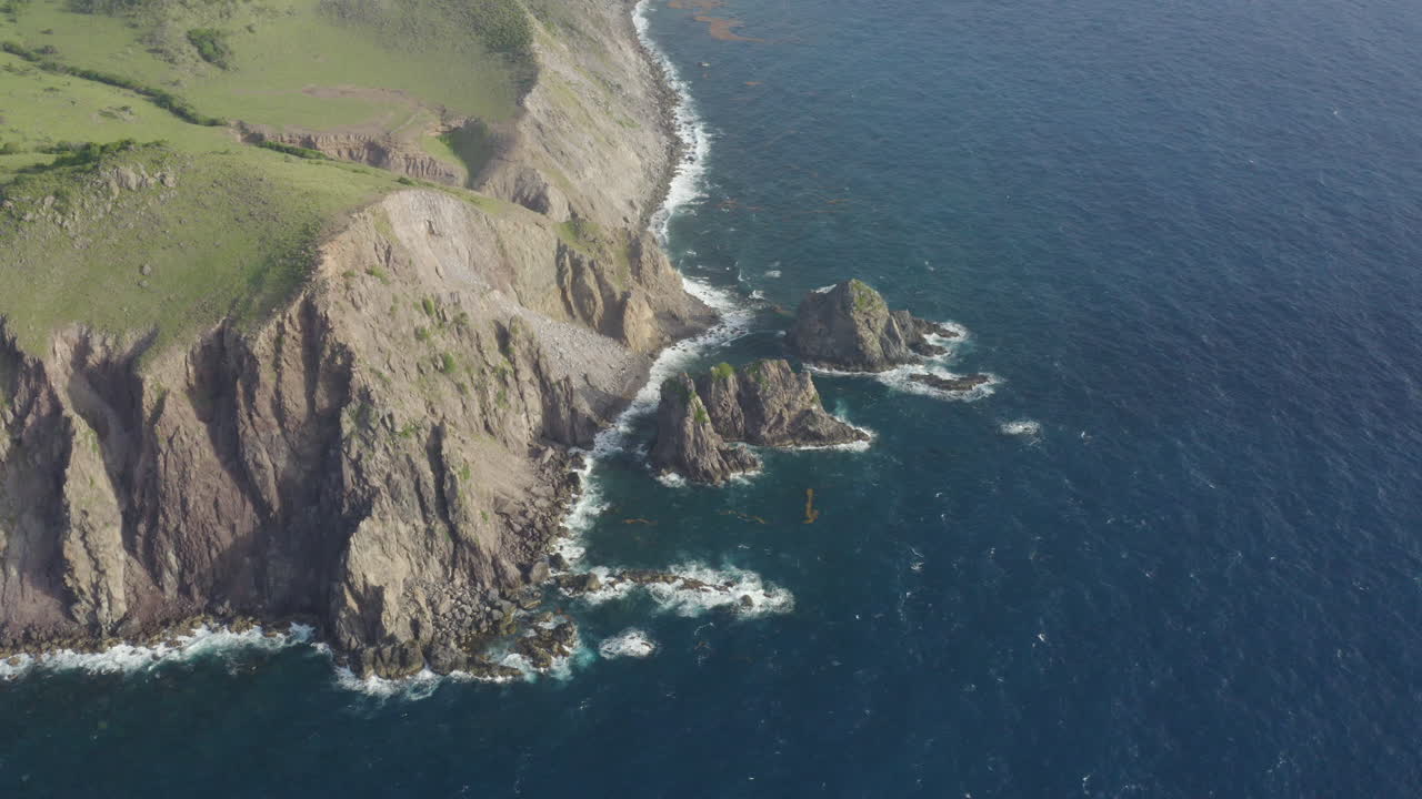 Abandoned Caribbean beach in the early morning. Smooth orbit, high up looking down at cliffs and three large rocks in the ocean. Part 2 of 2.4K UHD at 23.98 fps