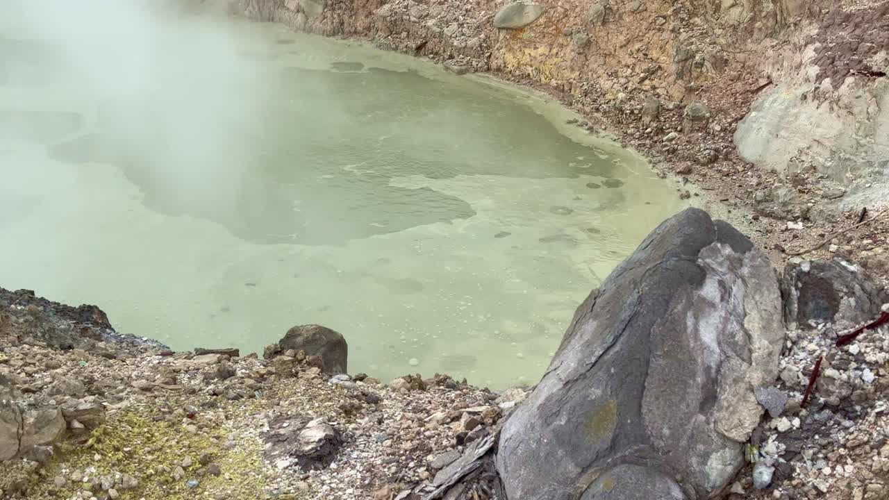 Boiling sulfur pool in a volcanic area releasing steam and gas. Hot geothermal activity showing the raw power of nature and extreme earth environments