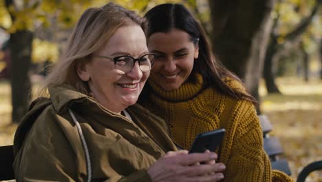 Mujeres-Caucásicas-Revisando-El-Teléfono-Móvil-En-El-Parque.