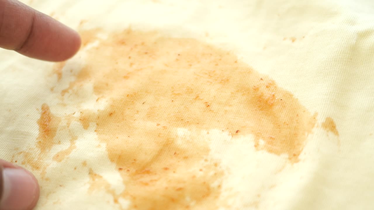 Finger Pointing at a Food Stain on a Light Yellow Shirt