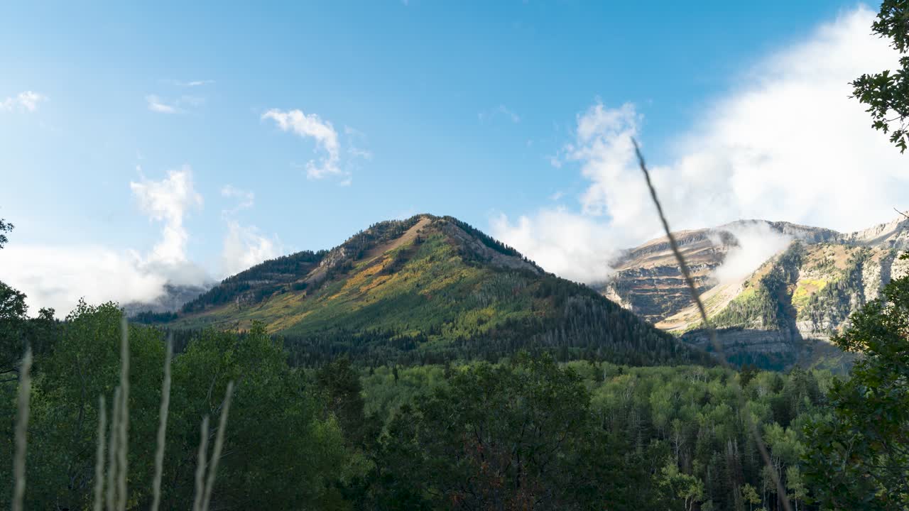 el amanecer ilumina una montaña en otoño mientras las nubes se arremolinan alrededor del pico - lapso de tiempo de gran angular