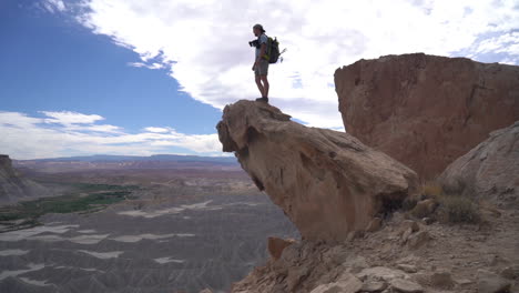 male photographer standing on rock above abyss and desert landscape, full frame