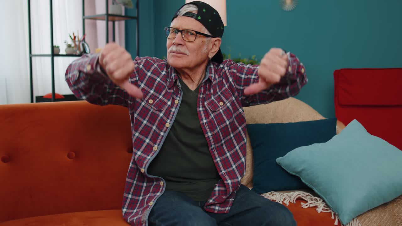 Senior man showing thumbs down sign gesture expressing discontent disapproval dissatisfied dislike