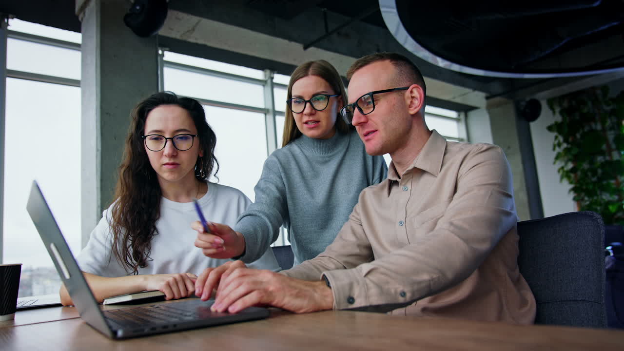 Business communication among the colleagues in office. Co-workers smile discussing the images on the screen.