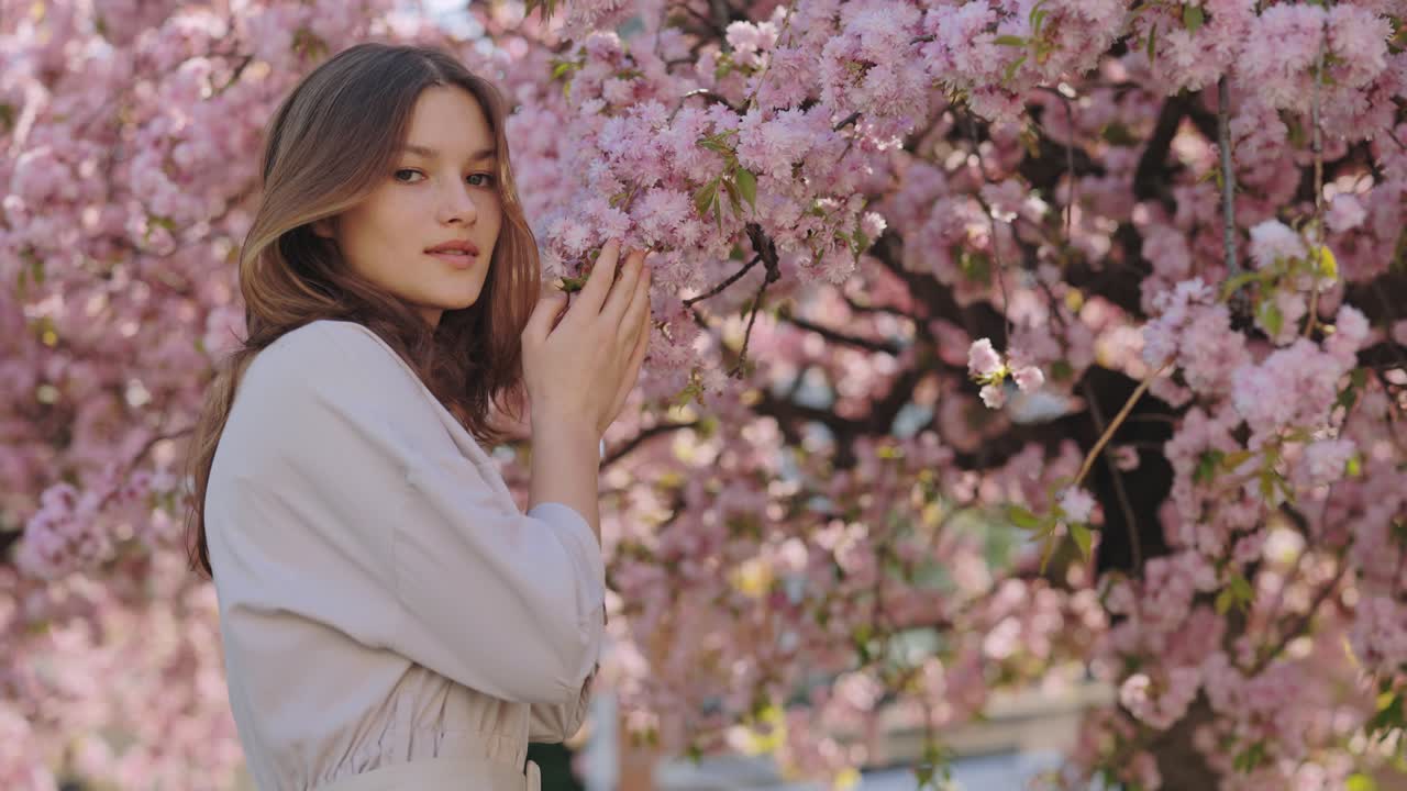 Woman in a light gray dress under a cherry blossom tree