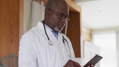 african american senior male doctor wearing white coat writing in notebook