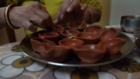 indian woman preparing a bunch of clay pots to light during the hindu festival of diwali