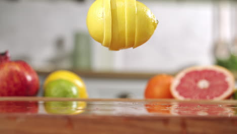 slow motion of sliced lemon falling on wet wooden board in a kitchen