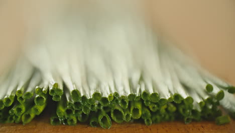 macro shot of a bunch of fresh chives laying on a wooden cutting board