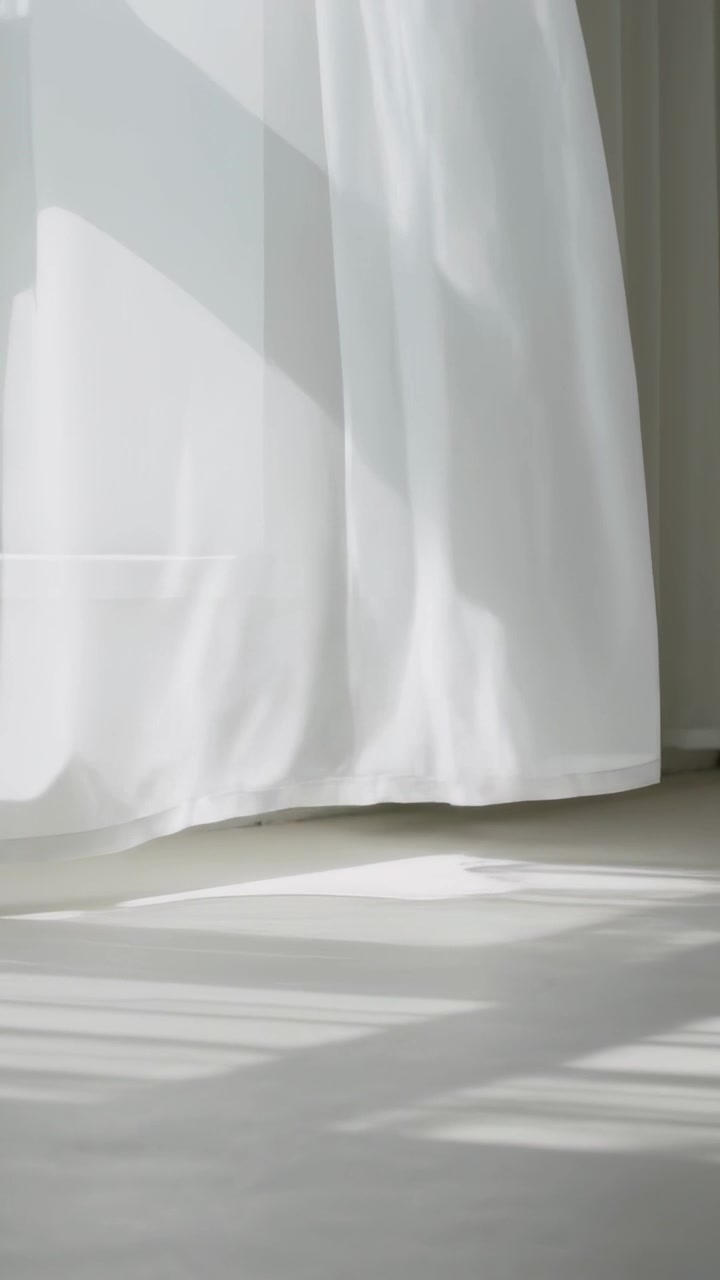 Video verticale: Tenda bianca trasparente che ondeggia, si muove verso l'interno alla finestra per una folata di vento, con la luce sul pavimento che si sposta.