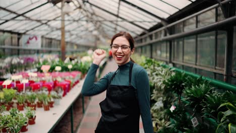 Young-woman-gardener-in-apron-dancing-in-greenhouse