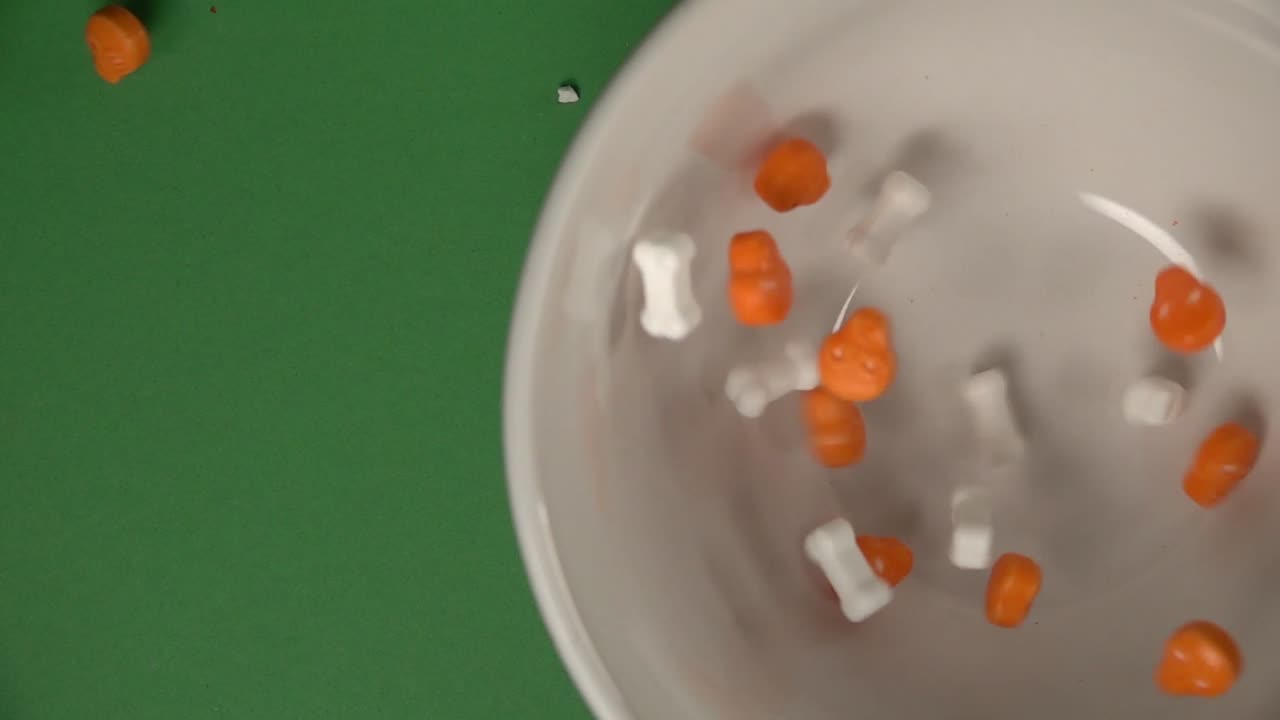 주황색 두개골과 뼈 모양의 사탕이 접시에 떨어지는 크로마 배경