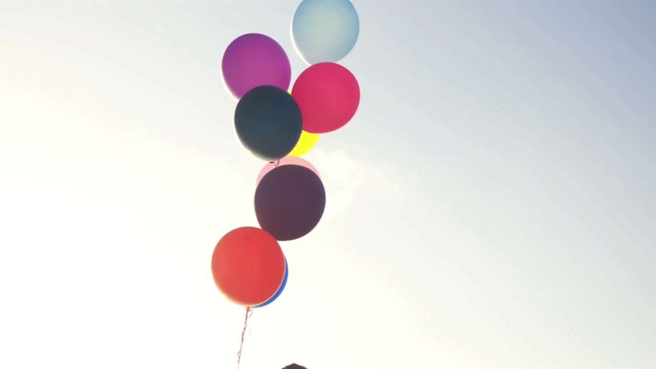 Mazzo di palloncini colorati che fluttuano contro un cielo sereno