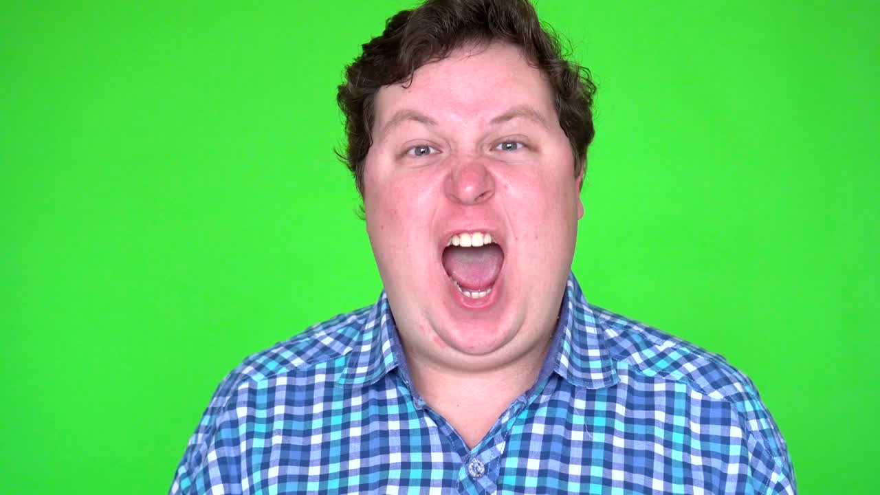 Close-up of angry fat man screaming against green background.