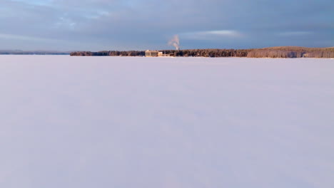 Aerial view low over snowy ice on lake Pielinen, sunny, winter evening in Finland