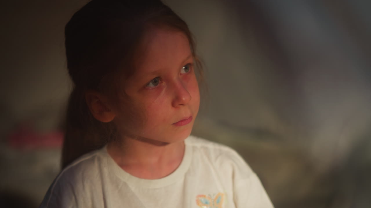 niño con ojos llorosos en un primer plano en una habitación semi-oscura. niña pequeña llora sufriendo violencia doméstica en un fondo borroso. niño triste con lágrimas en la cara