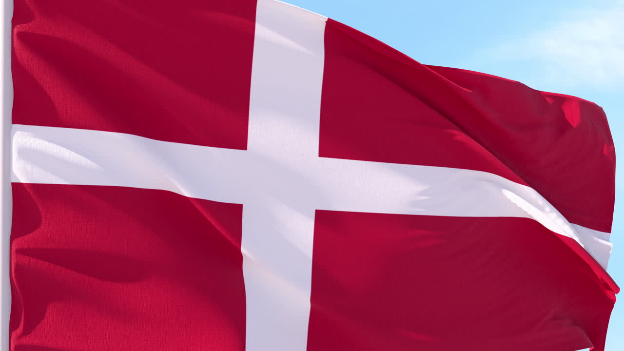Dannebrog vajer i vinden mod blå himmel