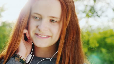 linda adolescente pelirroja escuchando música con auriculares