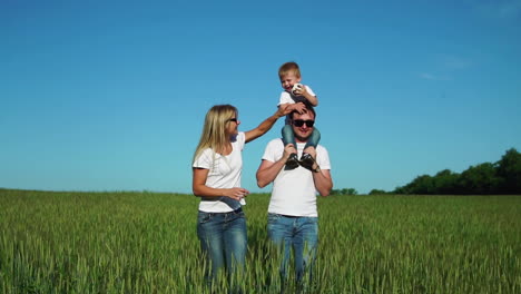 Wandernde-Familie-Mit-Einem-Kind-In-Weißen-T-Shirts-Auf-Dem-Feld