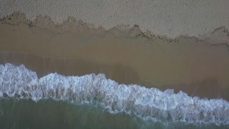 Amazing-top-aerial-view-of-exotic-vacation-beach-at-dusk,-waves-splash,-zoom-out