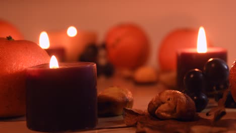 close up of an autumnal setting with leaves, mandarin, chestnuts, grapes and candles