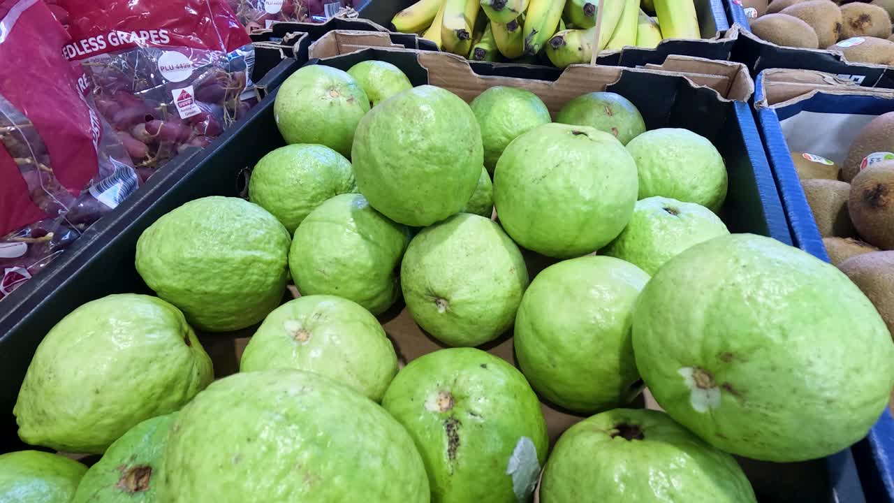 Close-up view of vibrant green guavas arranged in a market setting with natural lighting