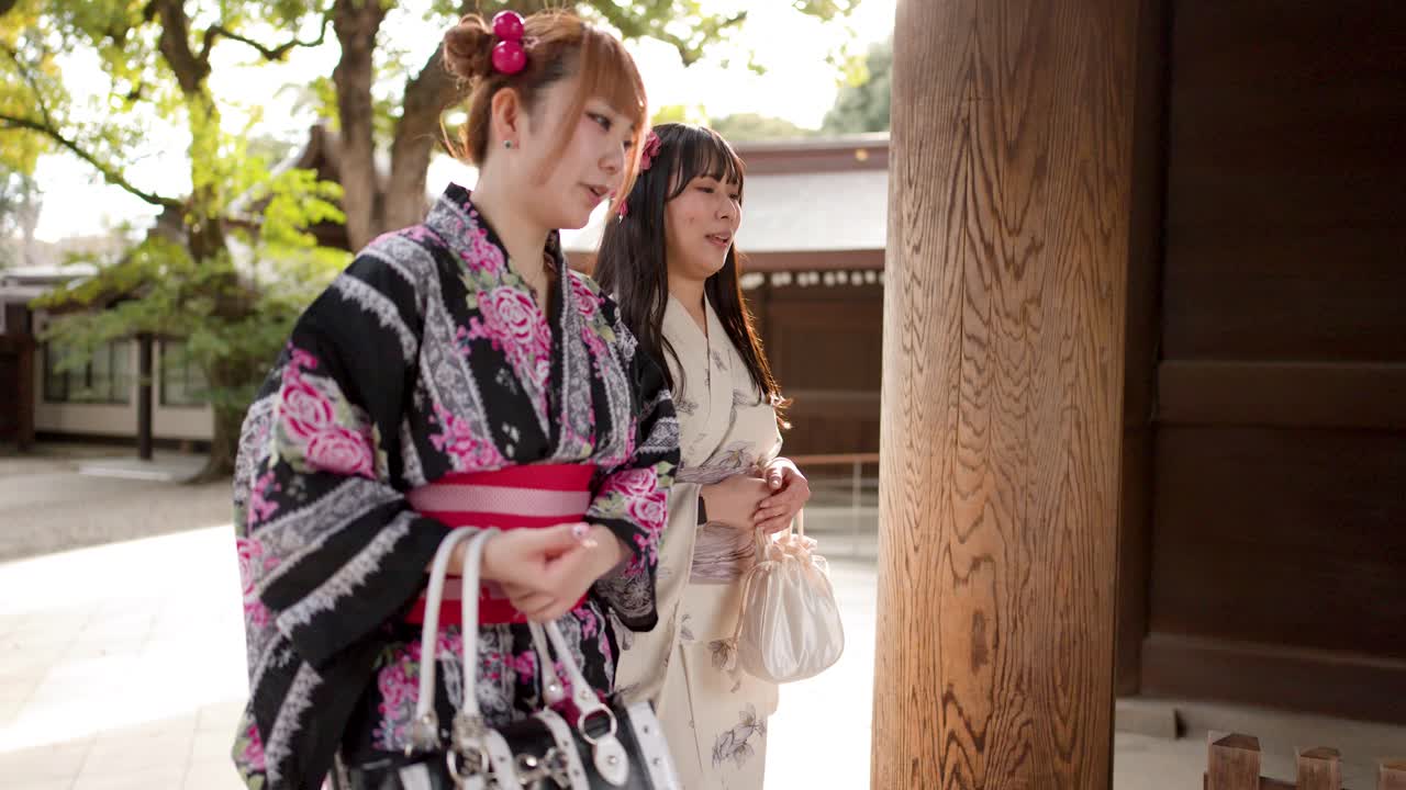 Deux amis en yukata traditionnel se promènent et discutent devant un sanctuaire shinto à Tokyo, au Japon.
