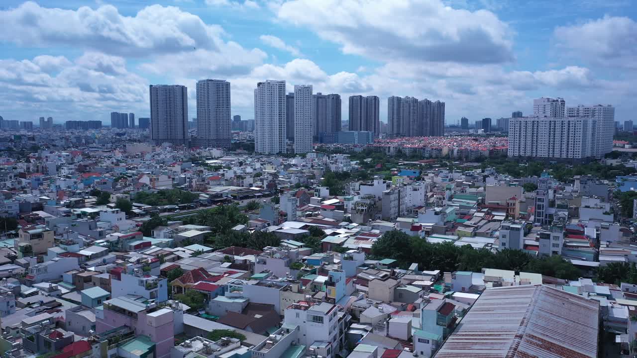 el avión no tripulado se inclina desde los techos de la zona industrial y residencial de alta densidad de la ciudad de ho chi minh, vietnam, a un amplio panorama con modernos edificios residenciales de gran altura y la carretera principal con cielo azul.