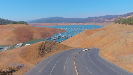 Erstaunliche-Luftaufnahme-über-Dem-Von-Der-Dürre-Betroffenen-Kalifornischen-Oroville-See-Mit-Niedrigem-Wasserstand,-Zurückweichender-Küstenlinie-Und-Gestrandeten-Hausbooten