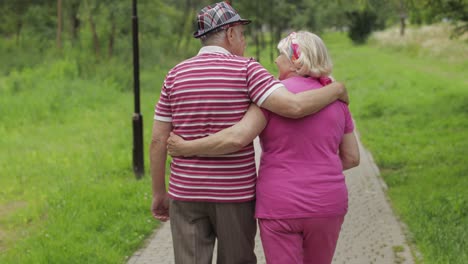 Senior-caucasian-couple-walking-in-park-embracing.-Elderly-man-walks-with-woman.-Husband,-wife