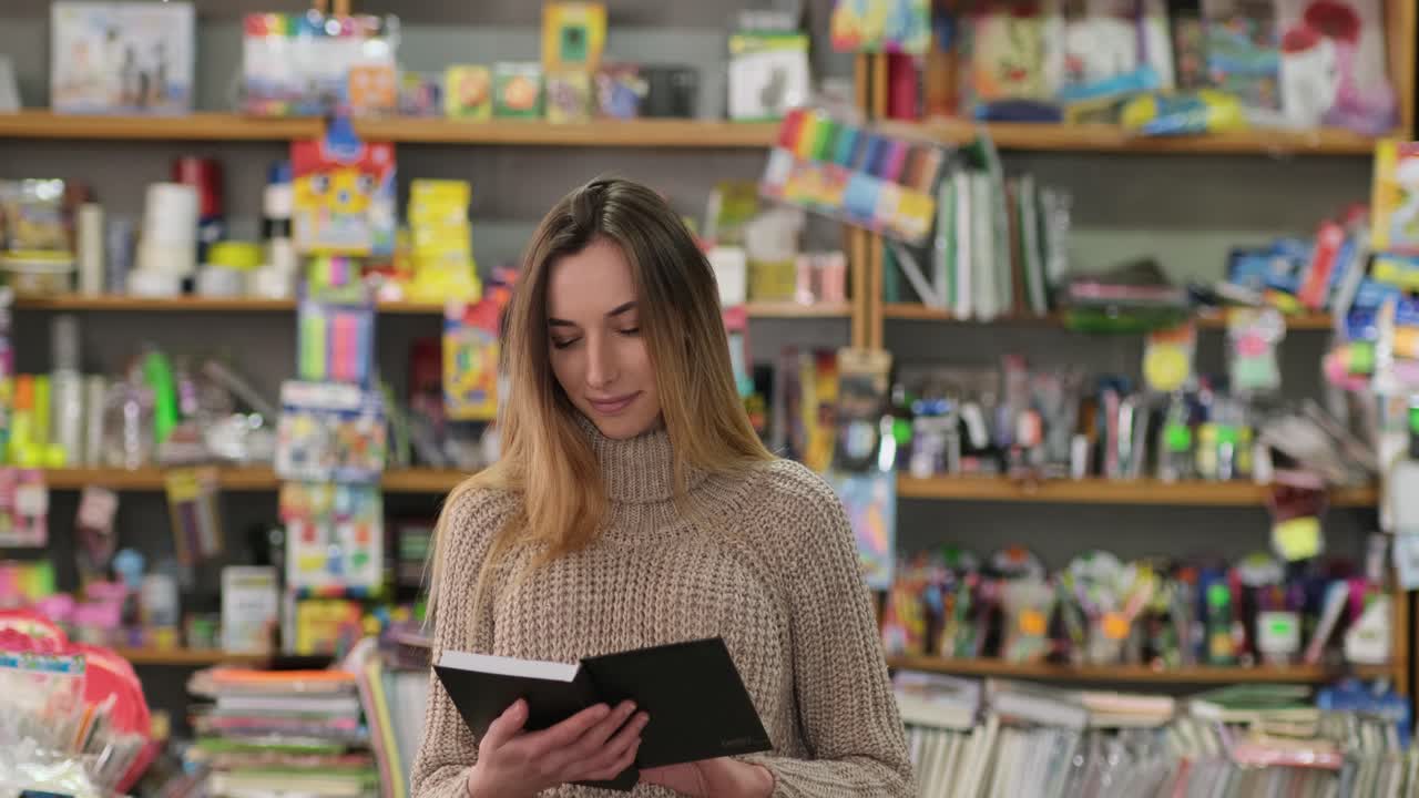 chica inteligente abre un libro en la biblioteca y sonríe