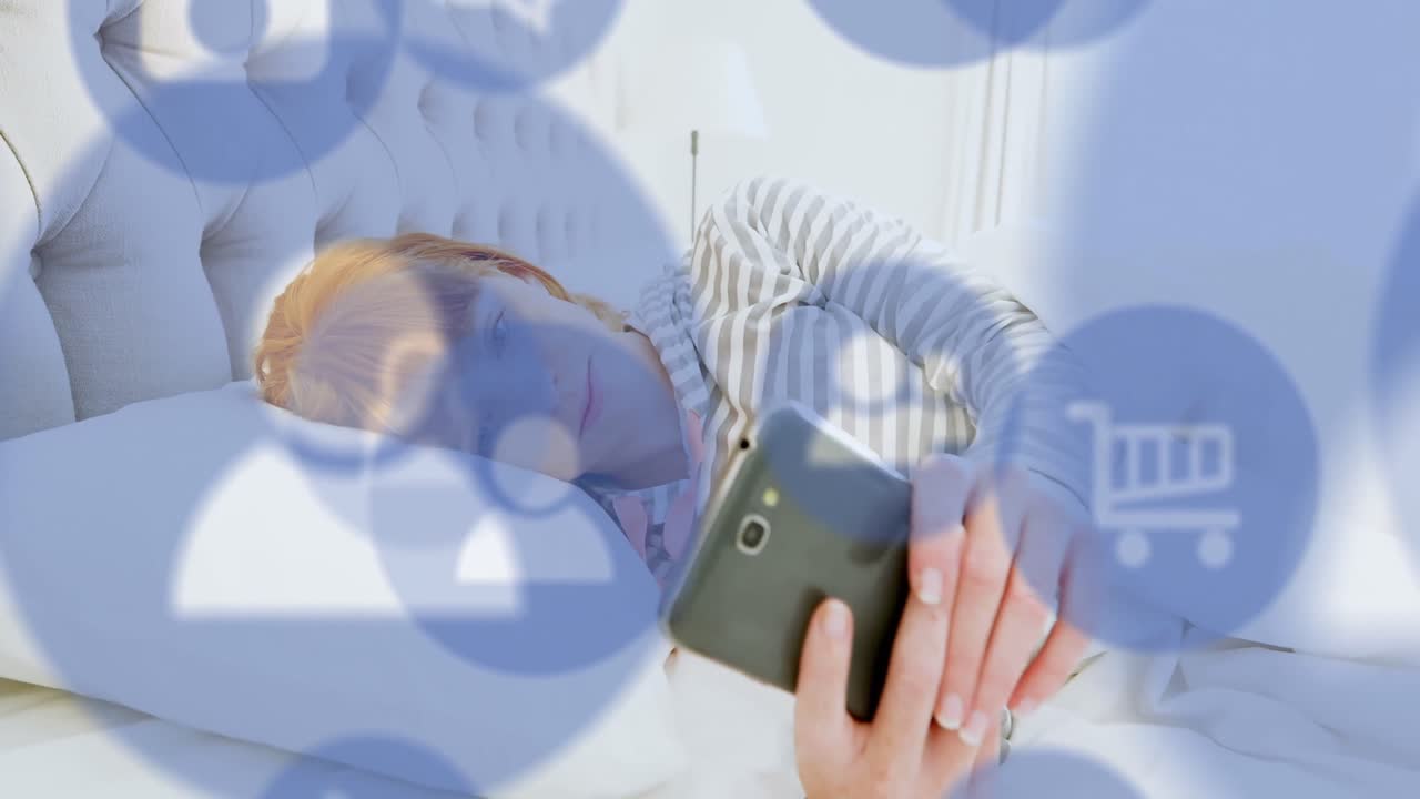 animación de múltiples iconos digitales sobre mujer caucásica usando teléfono inteligente en la cama en casa.