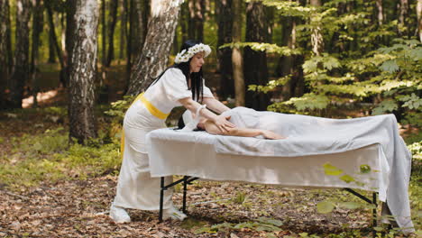 therapist female doctor making woman relaxing spa face massage with hands outdoors in the forest