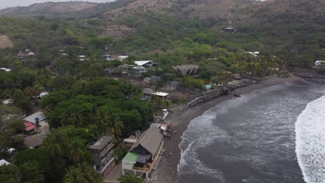 Quiet-dark-sand-beach-on-El-Salvador-coast,-surf-breaking-on-beach