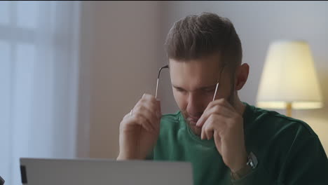hombre cansado ha terminado de trabajar con el portátil quitando las gafas y frotándose la cara relajándose después del trabajo con aparatos electrónicos fatiga de mirar la pantalla
