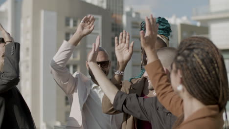 medium shot of excited colleagues giving high five to each other