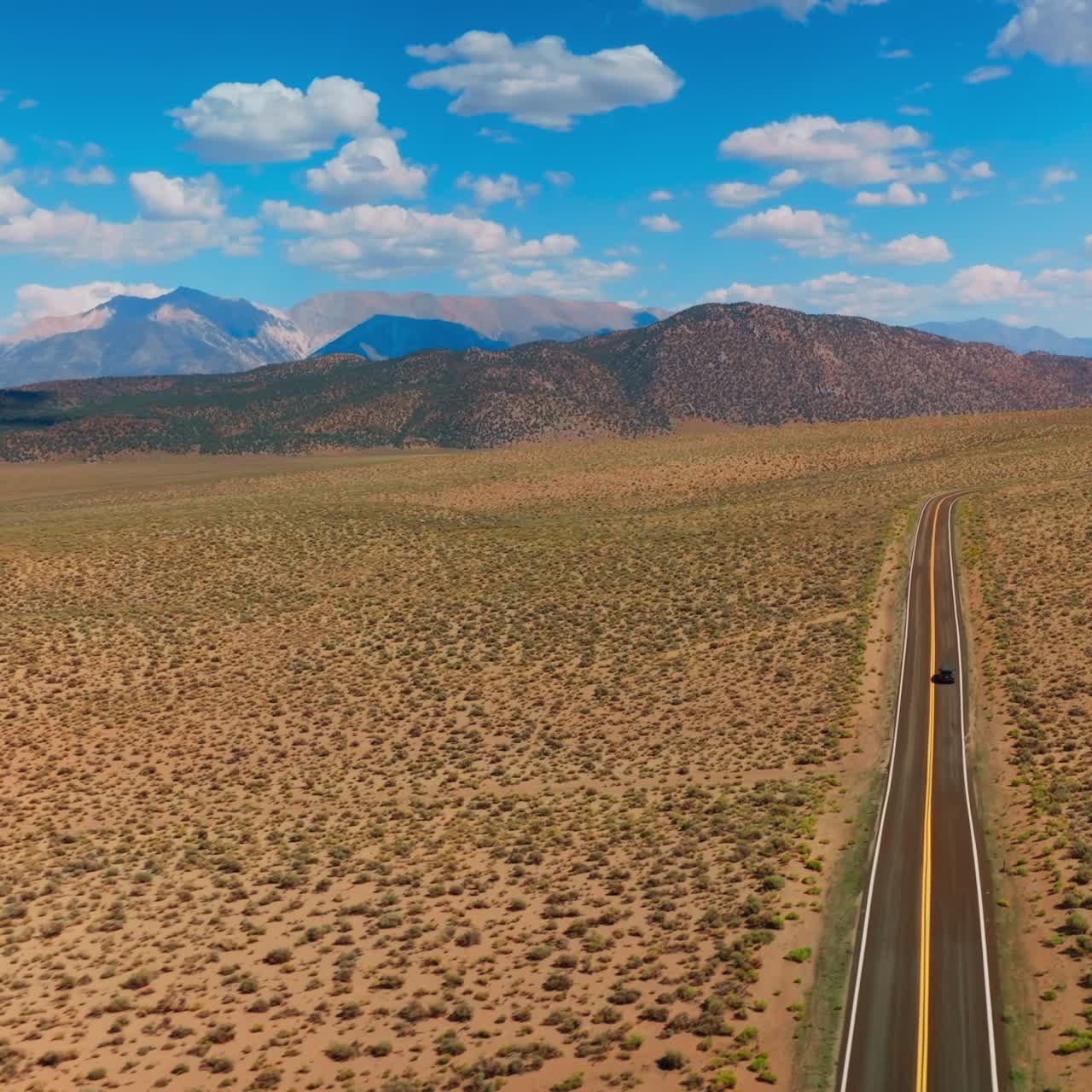 Motorway leading to the beautiful mountains of Nevada through the desert. Stunning landscape scenery on hot sunny day. Aerial view