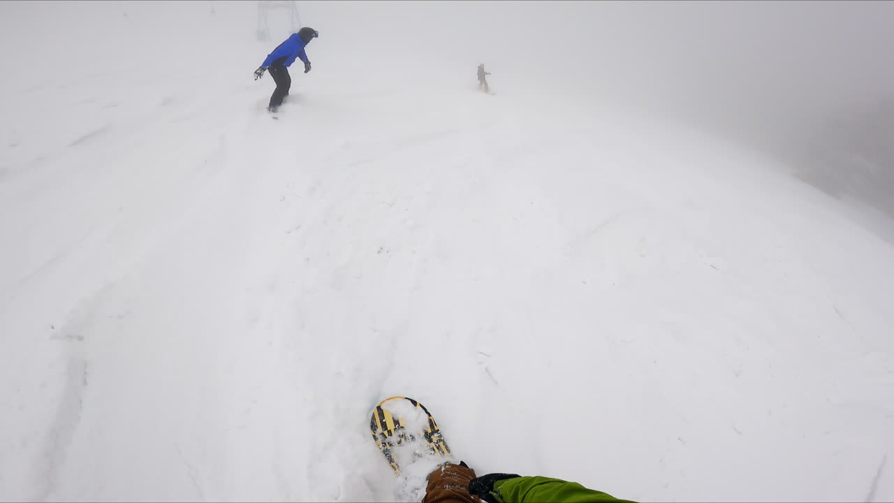 Snowboarding in the blizzard in mountains. Three sportsman go down the snowy slope.
