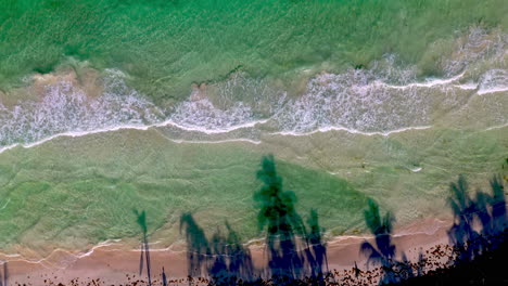 tiro de dron de ángulo descendente que se eleva en aguas claras del océano con olas rompiendo